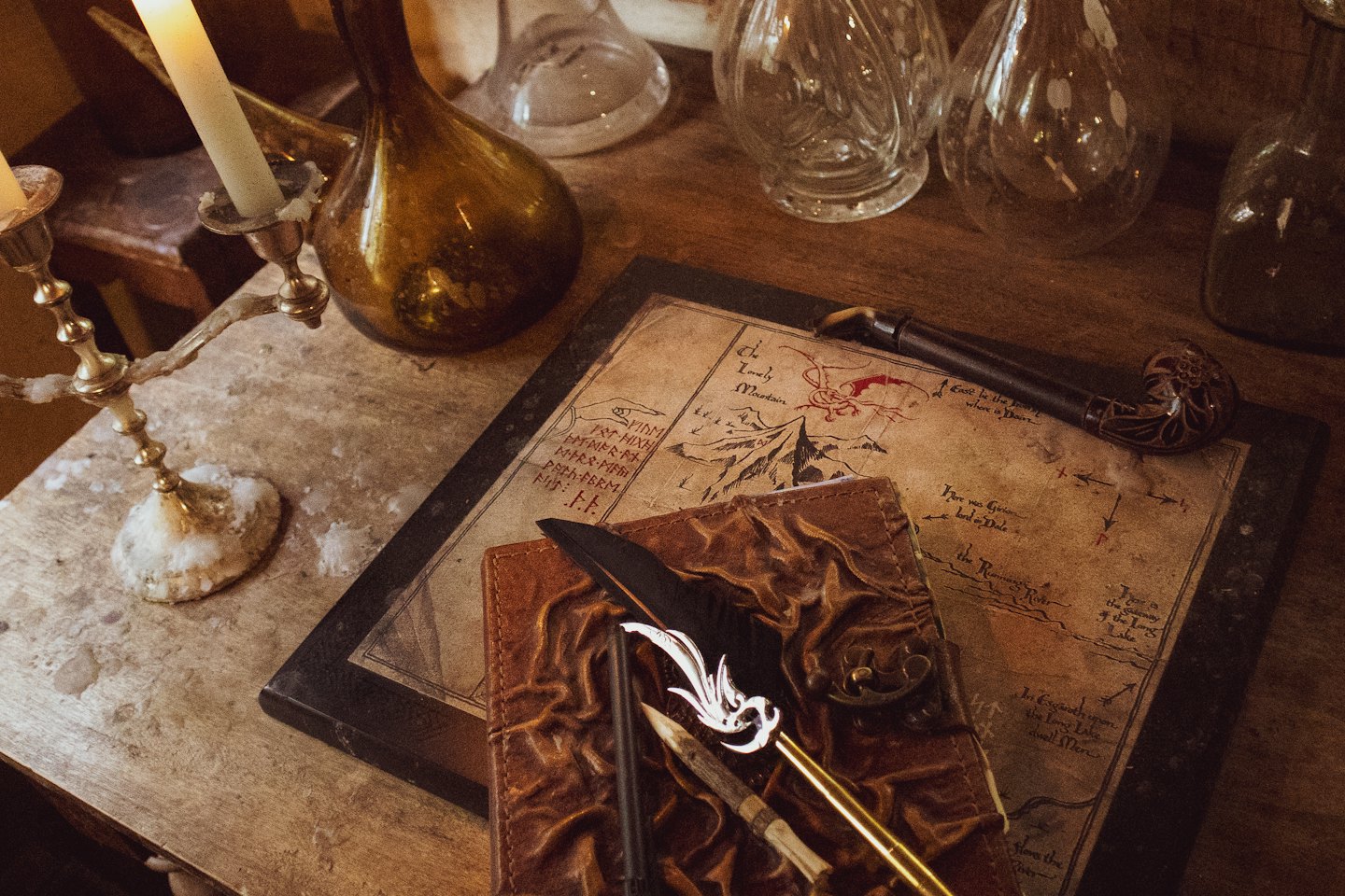 Rustic wooden table with fantasy map and old writing tools.